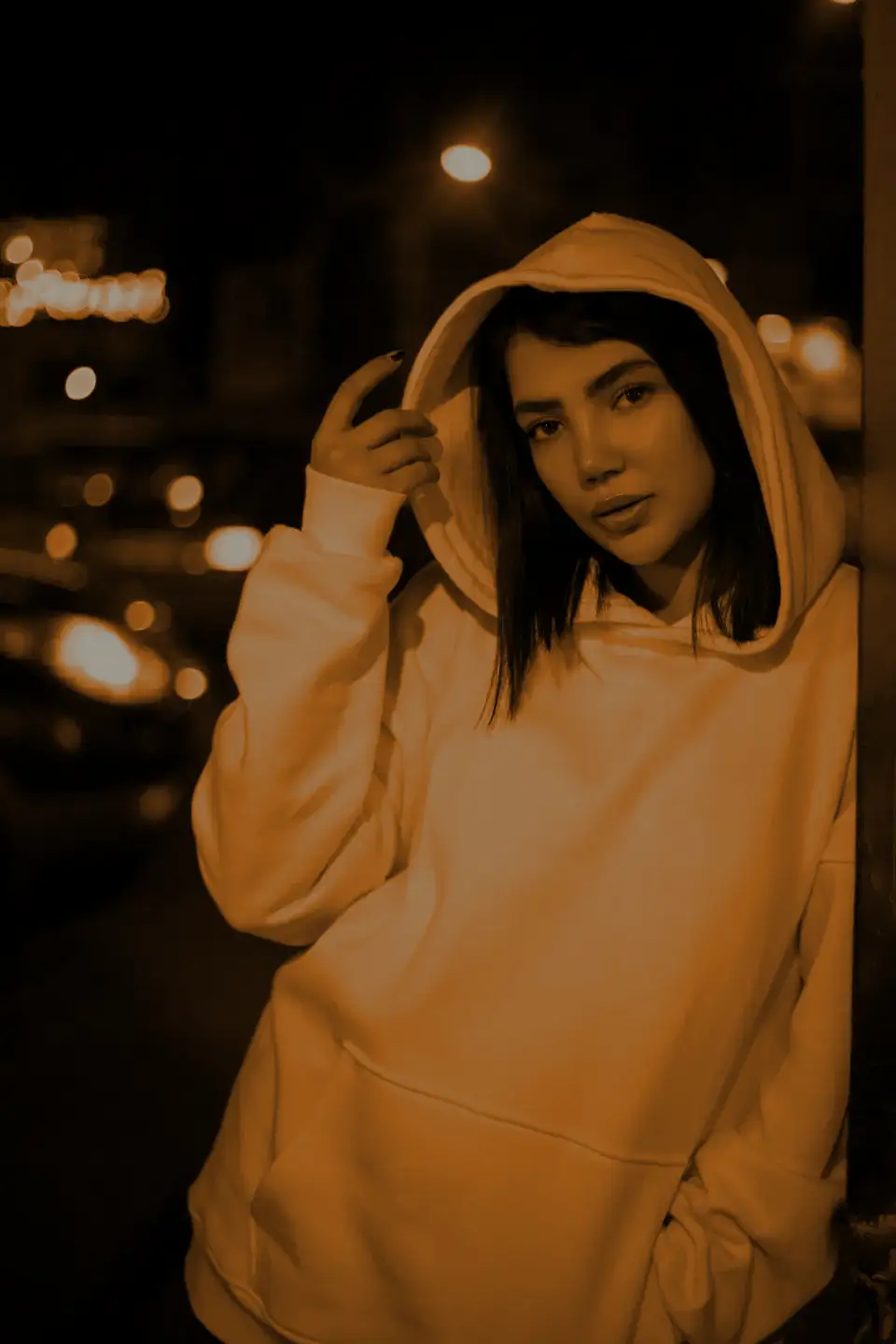 A woman in a white hoodie pulling up her hood in traffic light